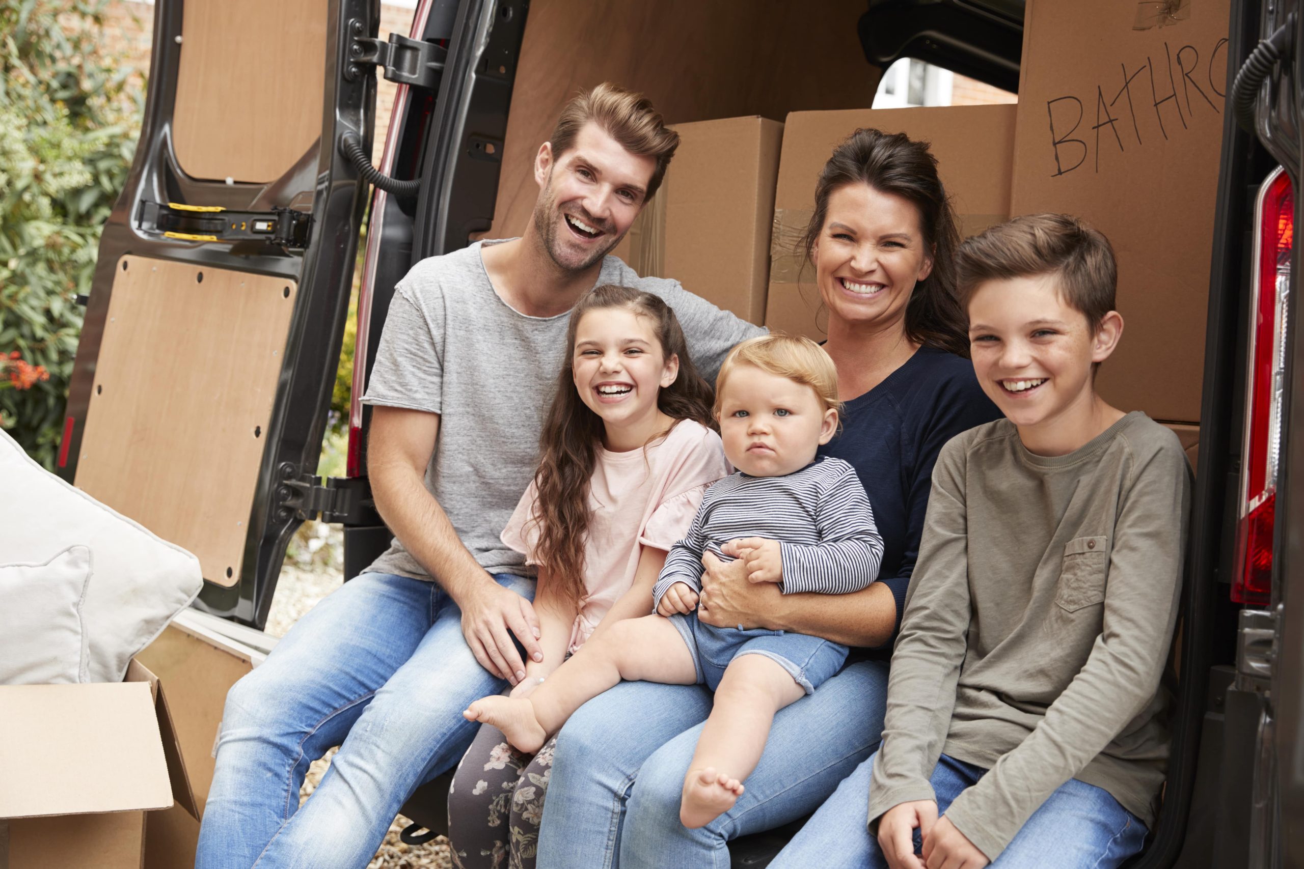 Happy family sitting in the back of a moving van
