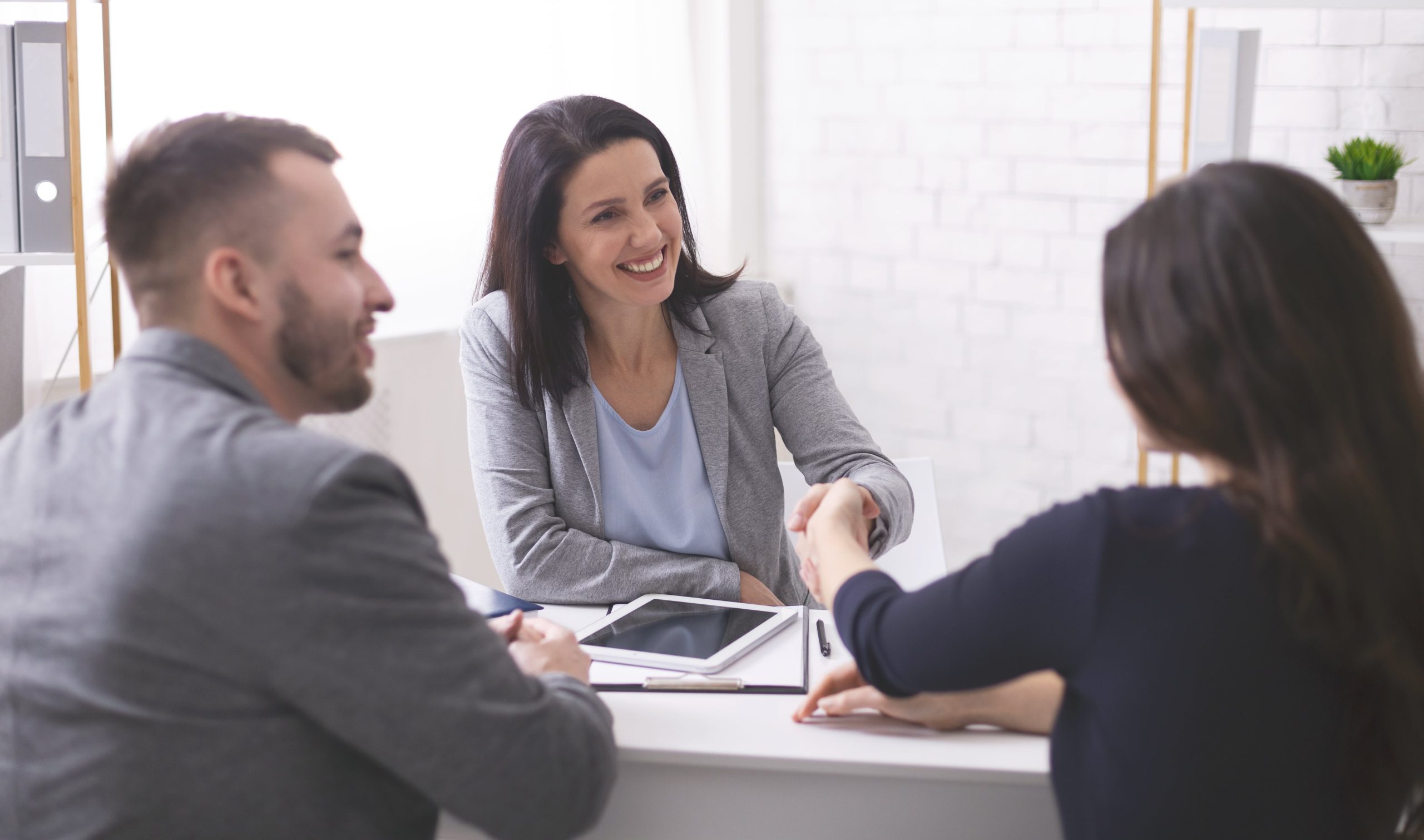 Business woman shaking hands with a young couple