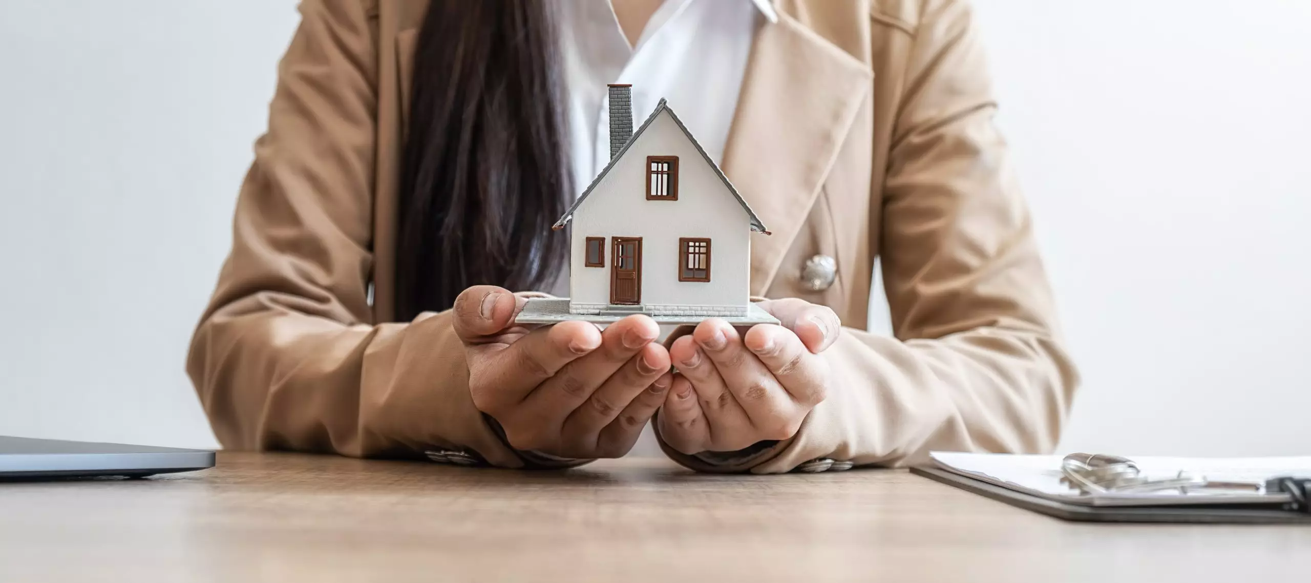 Real estate business woman holding up a miniature house