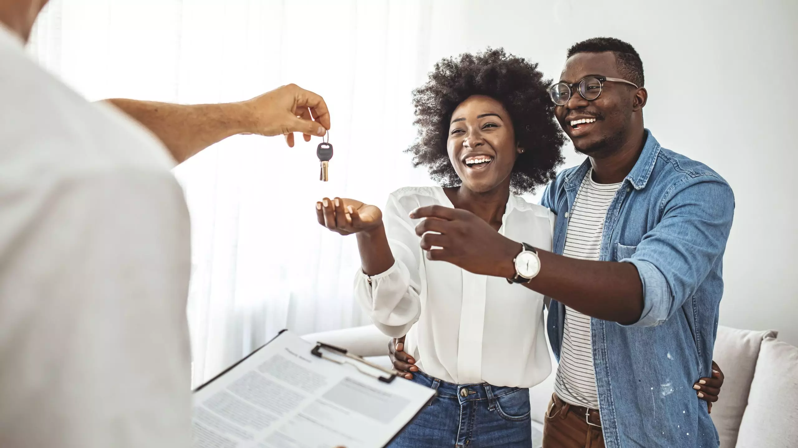 Young African American couple getting the keys for their new home from the realtor